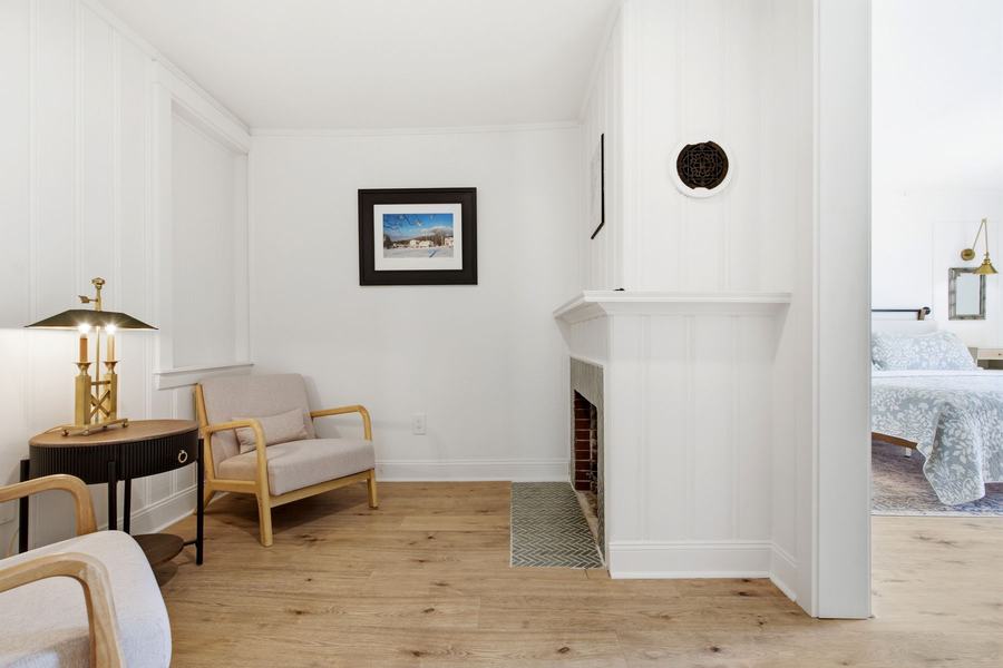 Bright private sitting room with cozy chairs and a decorative fireplace.