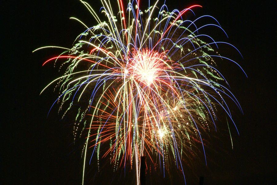 A lit sparkler held against the night sky on the Fourth of July